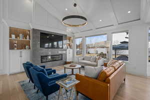 Living room with a fireplace, built in shelves, light hardwood / wood-style floors, and beam ceiling