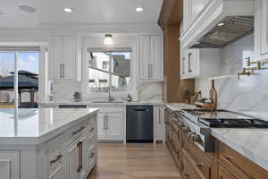 Kitchen featuring decorative backsplash, premium range hood, and white cabinetry