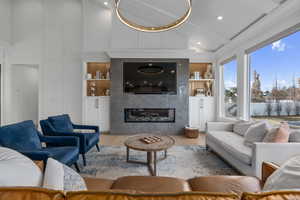 Living room with built in shelves, lofted ceiling, light hardwood / wood-style floors, and a tiled fireplace