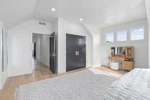 Bedroom with light hardwood / wood-style floors and vaulted ceiling