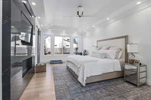 Bedroom with a tray ceiling, ceiling fan, a fireplace, and dark wood-type flooring