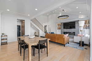 Dining room with light hardwood / wood-style floors, built in features, a fireplace, and ornamental molding