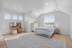 Bedroom with hardwood / wood-style floors and lofted ceiling