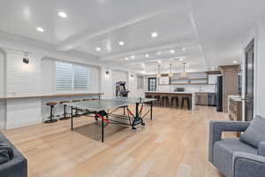 Playroom with beam ceiling, light hardwood / wood-style floors, and brick wall