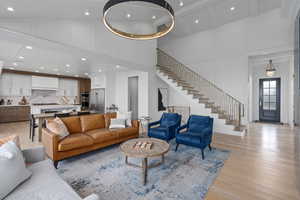 Living room with beam ceiling, light wood-type flooring, and high vaulted ceiling