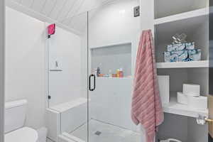 Bathroom featuring toilet and a shower with shower door