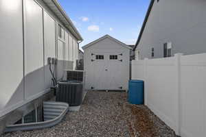 View of yard featuring central AC and a storage unit