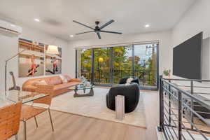 Living room featuring light hardwood / wood-style floors, a wall unit AC, and ceiling fan