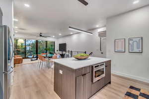 Kitchen with stainless steel refrigerator, ceiling fan, oven, decorative light fixtures, and a kitchen island