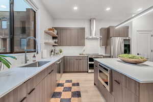 Kitchen with decorative backsplash, wall chimney exhaust hood, stainless steel appliances, sink, and light hardwood / wood-style flooring