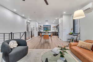 Living room with an AC wall unit and light hardwood / wood-style flooring