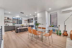 Dining room with a wall unit AC, light hardwood / wood-style flooring, and sink