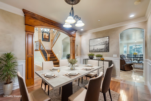 Virtually staged - Formal dining area with decorative columns, ornamental molding, and an inviting chandelier