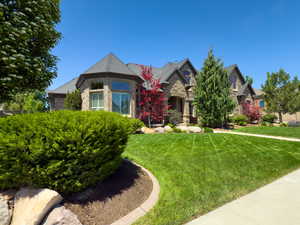 French country inspired facade with brick siding and a front yard