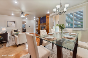 Virtually Staged - Dining room featuring ceiling fan with notable chandelier and a fireplace