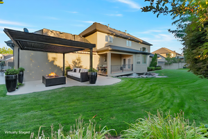 Virtually staged. Back of house with a patio, an outdoor living space with a fire pit, and a lawn