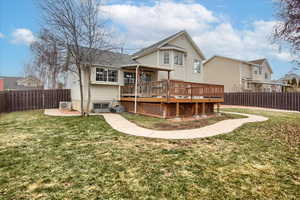 Back of property with central AC, a yard, and a deck