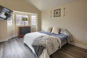 Bedroom with dark wood-type flooring and lofted ceiling, mountain views