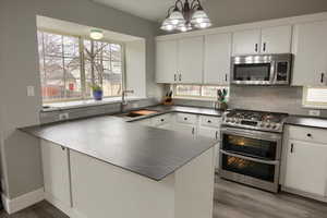 Kitchen featuring white cabinetry, double oven, sink, and appliances with stainless steel finishes