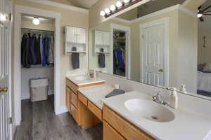 Bathroom featuring ceiling fan, vanity, ornamental molding, and hardwood / wood-style flooring