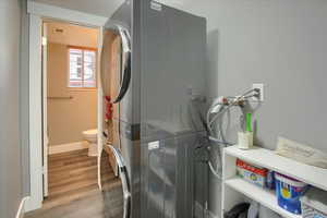 Laundry area with light wood-type flooring and stacked washer and dryer