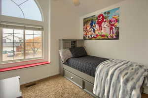 Carpeted bedroom with ceiling fan and vaulted ceiling