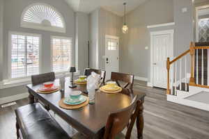 Dining area featuring high vaulted ceiling and dark wood-type flooring