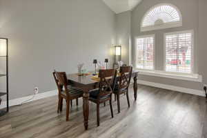 Dining space with high vaulted ceiling and hardwood / wood-style flooring