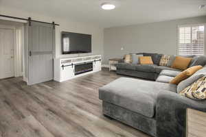 Living room with a barn door and wood-type flooring