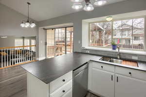 Kitchen featuring white cabinets, sink, vaulted ceiling, stainless steel dishwasher, and a chandelier