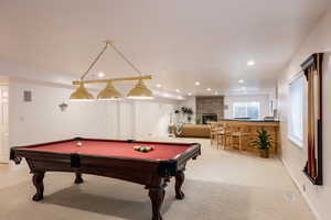 Recreation room with a fireplace, light carpet, and pool table