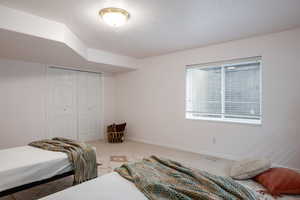 Carpeted bedroom with a textured ceiling and a closet