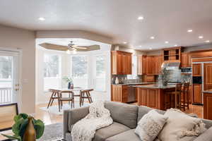 Kitchen featuring ceiling fan, sink, backsplash, built in appliances, and a kitchen island