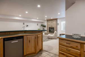 Kitchen with light carpet, a brick fireplace, and stainless steel dishwasher