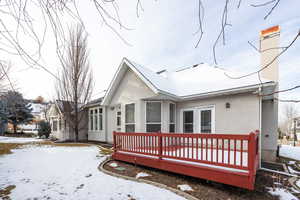 Snow covered rear of property with a deck