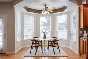 Dining area featuring a raised ceiling, ceiling fan, plenty of natural light, and light wood-type flooring