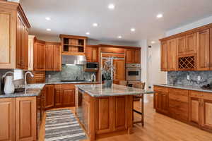 Kitchen with a kitchen breakfast bar, sink, built in appliances, a kitchen island, and extractor fan