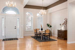 Dining room with light hardwood / wood-style floors and an inviting chandelier