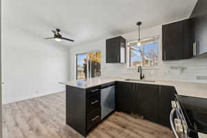 Kitchen with appliances with stainless steel finishes, kitchen peninsula, sink, decorative light fixtures, and tasteful backsplash