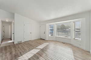 Spare room with light wood-type flooring and lofted ceiling