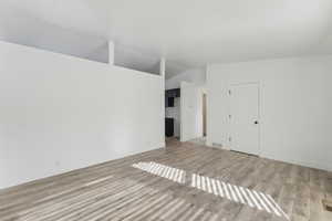 Unfurnished living room with light hardwood / wood-style floors and lofted ceiling