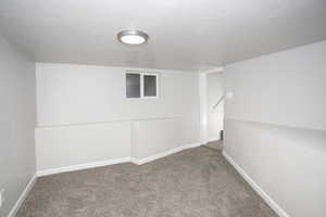 Basement with carpet flooring and a textured ceiling