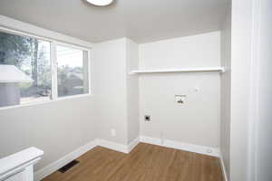 Clothes washing area with hookup for a washing machine, hardwood / wood-style floors, and hookup for an electric dryer