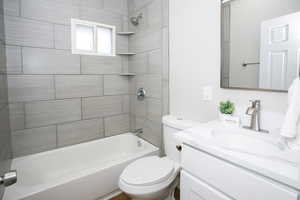 Full bathroom with tiled shower / bath, vanity, and toilet