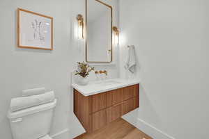 Bathroom with hardwood / wood-style floors, vanity, and toilet