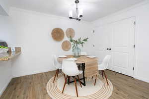 Dining area featuring ornamental molding, wood-type flooring, and an inviting chandelier