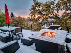 Snow covered patio featuring a fire pit and a balcony