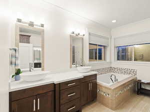 Bathroom featuring tile patterned flooring, vanity, and tiled tub