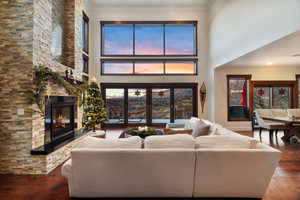 Living room featuring a stone fireplace, a healthy amount of sunlight, dark hardwood / wood-style floors, and ornamental molding