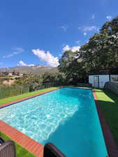 View of swimming pool featuring a lawn and a mountain view